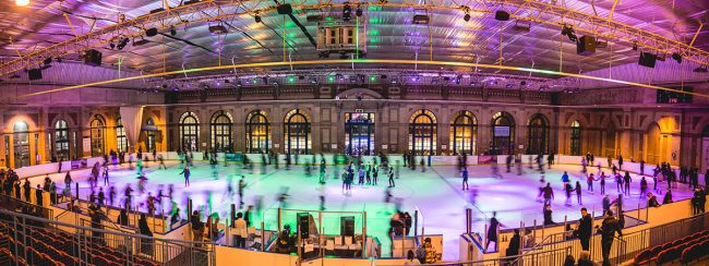 People ice skating at Alexandra Palace in motion with green and purple lights.