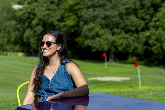 Woman sat on a golf course in the sun.