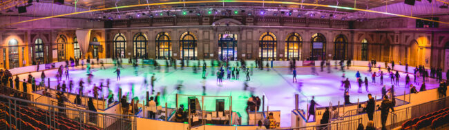 People ice skating at Alexandra Palace in motion with green and purple lights.