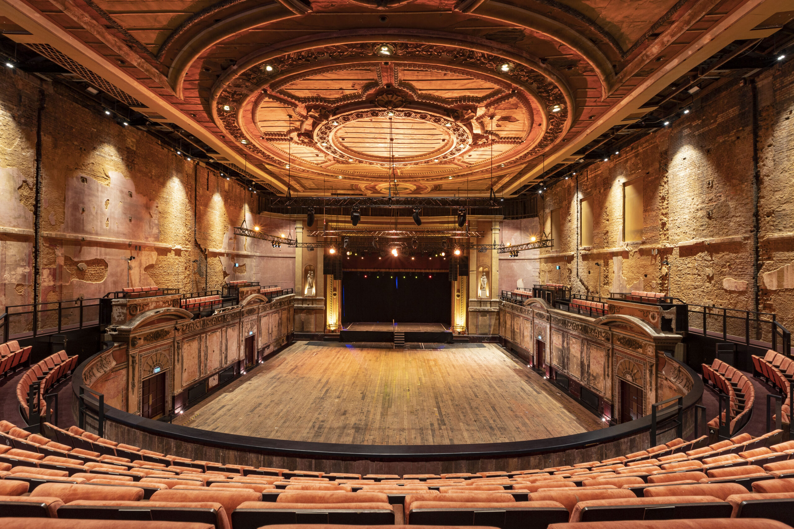 A grand empty theatre with orange seats,