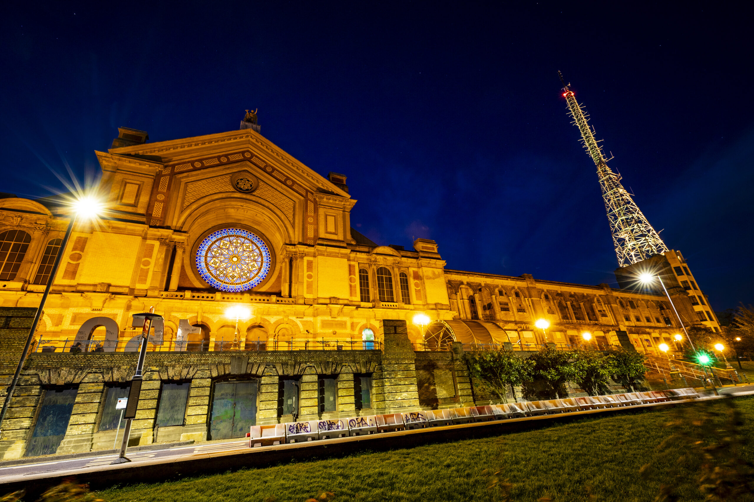 The frontage of Ally Pally lit up at night with a clear night's sky.