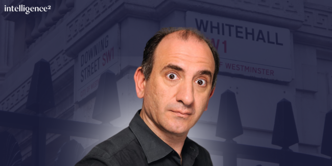 A person with a surprised expression in front of blurred street signs for Downing Street and Whitehall. The tone is comedic and inquisitive.